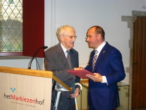 wethouder Arjan van der Weegen biedt Herman Huismans het eerste boek aan