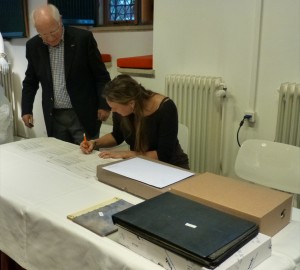 Mireille Franken tekent namens Markiezenhof voor ontvangst. Op de voorgrond is een deel van het archief zichtbaar, inclusief het handgeschreven 'dagboek'' van Hubertus Beckers