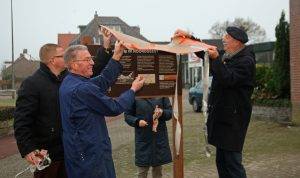 Het bord wordt met vereende krachten onthuld: Wethouder van de Velden, bewoner Van Loon, werkgroepleden Ria Weyts (achter bord) en Eric Goossen